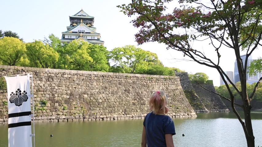 Tourist enjoys in front of Osaka Castle and Gokurakubashi Bridge at sunset. Freedom and asia travel concept. Defocused background. Osaka Castle is one of the most famous landmarks in japan. Light shot