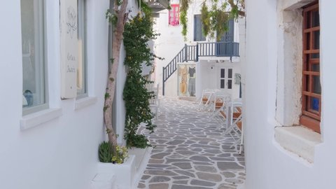 NAOUSA, GREECE - MAY 27, 2019: Walking with steadycam in picturesque street with whitewashed houses with blooming bougainvillea flowers of Naousa town in famous tourist attraction Paros island, Greece