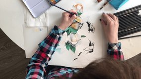 Young girl artist paints with watercolor on paper