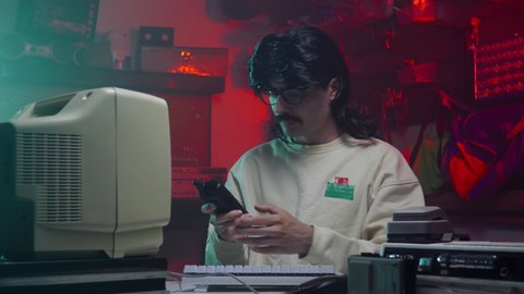 Computer nerd from the '80s or '90s using a cell telephone to place a call. Retro scene with vintage colors and atmosphere.