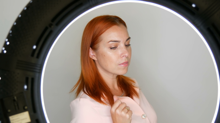 Beautiful red-haired adult middle-aged female model posing in front of the camera in the studio