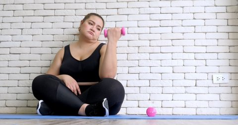 Overweight young woman in sportswear  bored with exercise to lose weight