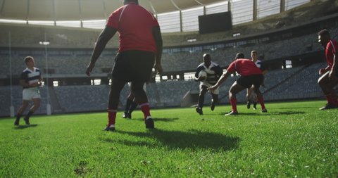 Front view of diverse rugby players playing rugby match in stadium. They are tackling each other in slow motion