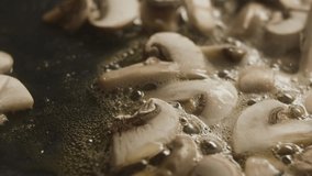 Close-up of sliced champignon mushrooms fried in pan. Slow motion video