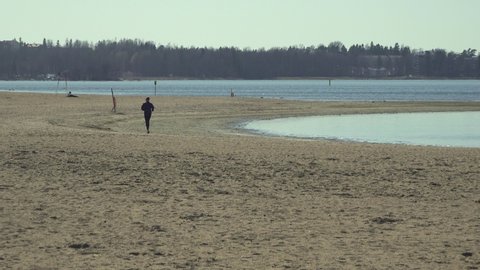A man jogging on a deserted urban beach