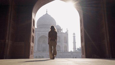 Happy young woman walking and wandering at the famous Taj Mahal at sunrise feeling free, Agra, India. People travel Asia concept 