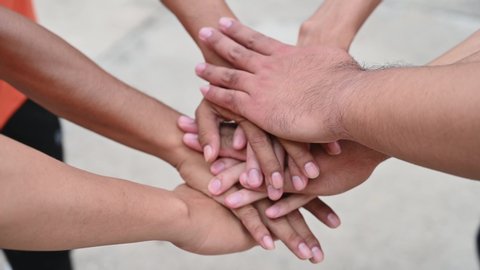 A group of friends extended their arms to touch their hands for unity.