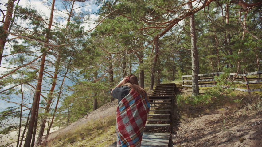 Young Beautiful Girl Walking Up the Wooden Stairs on the Edge of a Pine Forest and Going From a Beautiful Blue Sea Landscape. Warm Sunny Day with Nature. She