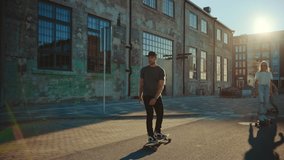 Group of Girls and Boys on Skateboards Through Fashionable Hipster District. Beautiful Young People Skateboarding Through Modern Stylish City Street. Moving Slow Motion Portrait Camera Shot