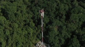 Telecommunication antenna tower with base transmitters over the forest 4K aerial video