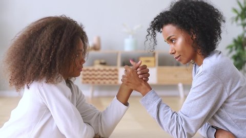 Afro different ages women older younger girls compete arm wrestle. Competition between females, daughter mother generations confrontation, generational gap opinions difference misunderstanding concept