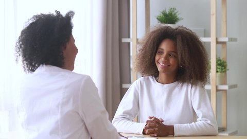 Rear view physician in white coat talks with teenager sit at doctors office table focus on pre-teen girl listens friendly medical worker psychotherapist, therapist counsellor, therapy session concept