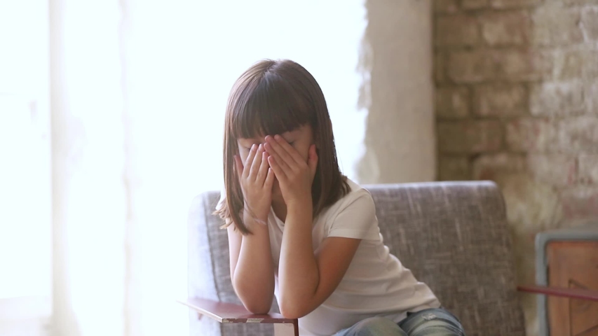 Six years old daughter sit on chair at home feels resent about punishment of parents, kid girl waiting suffer from boredom thinking lost on sad thoughts, little person problems frustrations concept  | Shutterstock HD Video #1034756375