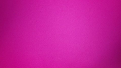 A wine glass rolling up, on and off the screen, top down view on a hot pink background. Looking down at an empty wineglass rolling across solid hot pink, slow motion shot.