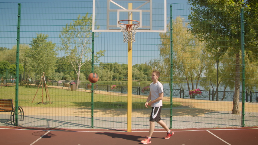 Closeup portrait of young attractive caucasian male basketball player throwing a ball in the hoop on the court win the park