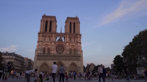 PARIS, FRANCE - June 17 2019: Real time establishing shot of Notre Dame de Paris at sunset. Crowds of tourists near gothic cathdreal Notre Dame de Paris, June 17, 2019 in Paris, France.
