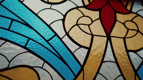 Stained glass window close-up, with red, orange and blue colours.