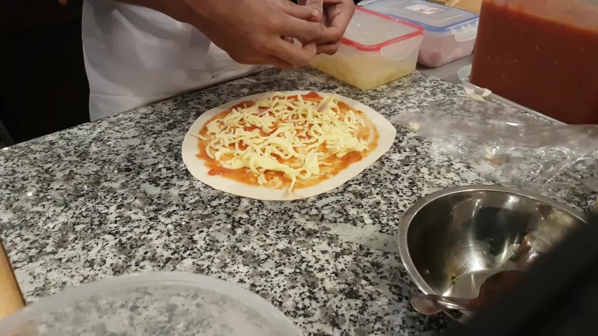 Man Adding Ham On Pizza, Cooking At Kitchen Table In Pizzeria