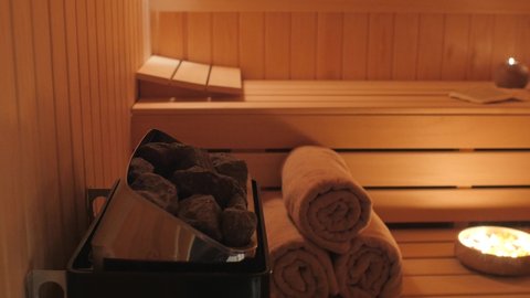 empty sauna room with burning candles with towel and hot stones