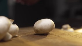 Macro video of the cook slices raw champignons on the wooden board, cooking the mushrooms, vegetarian food, macro food, process of cooking, meal with champignons, Full HD Prores 422 HQ