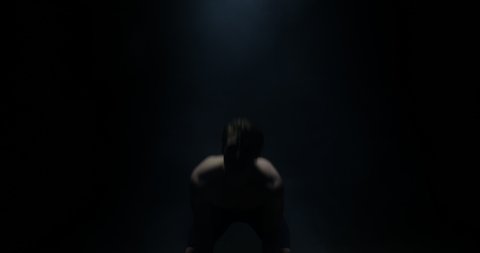 Sweating Shirtless Male Weightlifter Looking At The Camera And Lifting Weights Towards Camera In A Dark Background 