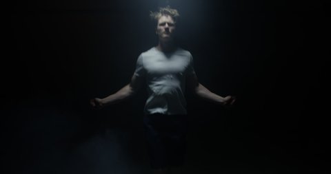 Energetic Male Skipping Training In White T-Shirt And Dark Background With Spotlight