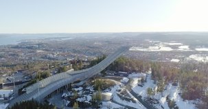4K aerial video of the famous Holmenkollen, an international symbol of ski jumping, with a beautiful background view of mountains and Oslo city.