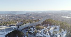 4K aerial video of the famous Holmenkollen, an international symbol of ski jumping, with a beautiful background view of mountains and Oslo city.