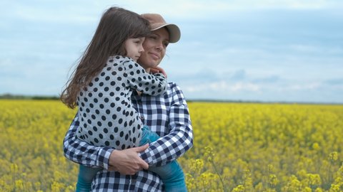 Mother holds her daughter in her arms. Little girl hugs mother in nature.