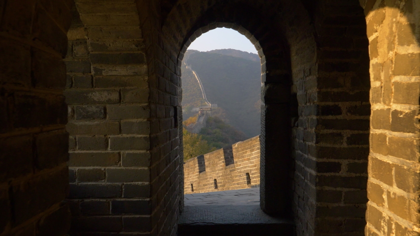 SLOW MOTION CLOSE UP: Dark corridor leads to a breathtaking view of the Great Wall at sunset. Golden autumn morning sun beams shine into the corridor leading to a walkway atop the Great Wall of China.