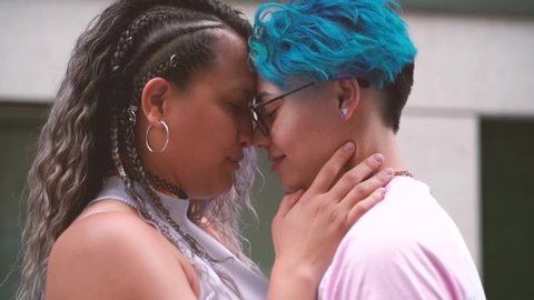 Sweet and tender kiss between two women in love. Public shown of affection. Free love to all sexual orientation. Gay young relationship. Blue short hair lesbian icon.