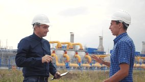 teamwork. industry gas production station concept. slow motion video. two engineers in helmets shaking hands on a gas supply business contract. lifestyle two workers work at the factory in helmets