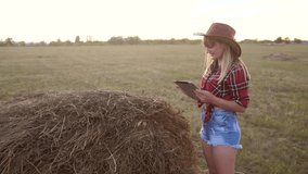 smart farming slow motion video concept. girl agronomist holds tablet touch pad computer in hay field stack is studying and examining crops before harvesting. woman Agribusiness concept. female farmer