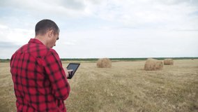 smart farming agriculture concept. man farmer studying a haystack in a field on a digital tablet. lifestyle slow motion video. male agronomist botanist farmer working in the field