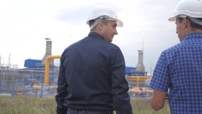 teamwork. industry gas production station concept. slow motion video. two engineers in helmets are studying working with a digital tablet in factorygas supply business contract. lifestyle two workers