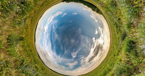 Little planet Transformation with curvature of space. Abstract torsion and spinning of full flyby panorama among fields in sunny evening with awesome clouds