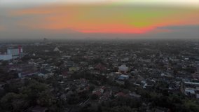 Cinematic aerial footage view of Yogyakarta city, Indonesia with buildings, houses and beautiful sunset golden sky background
