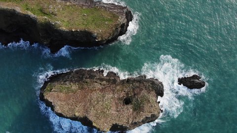 Waves crashing against the cliffs of basset cove, while seagulls perch on top and circle in the air. 

Cornwall - England (Birds eye view)