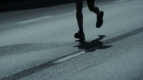 Running marathon. Close up on runners feet. Shadows on the street.