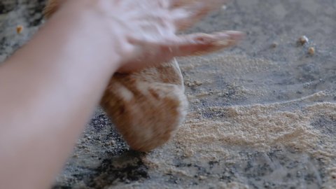 Woman hands kneading whole wheat dough on floured countertop
