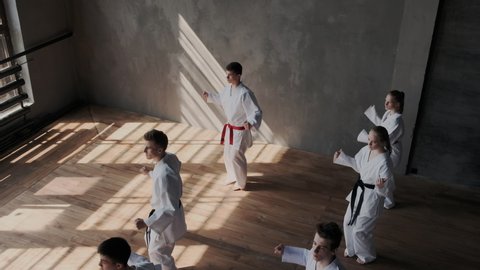 A group of skillful battlers in white kimonos synchronously performs a set of taekwondo exercises with special breathing technology. General view. Mixed race. View from above.