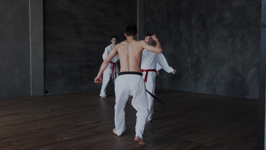 Brave powerful asian guy fighting alone against three strong warriors in white kimono. He perform active martial tricks and makes forceful attack. Slow motion and rapid. Part 1. Royalty-Free Stock Footage #1034854601