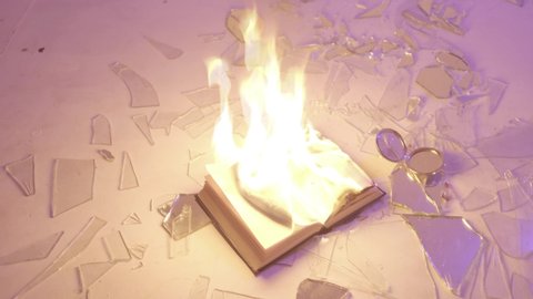 the book lies on the floor among broken glass and burns