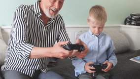 Emotional grandfather plays with his grandson in computer games with a joystick.