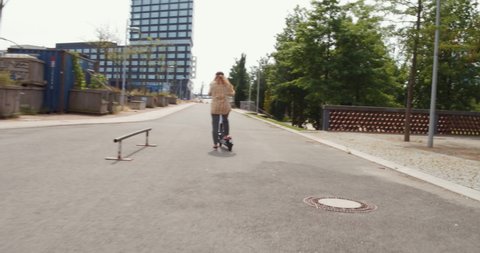 Young girl rides an electric scooter or e scooter in hamburg city germany, ecological e mobility in the urban city, 4k Steady Follow Chase Shot, modern transportation