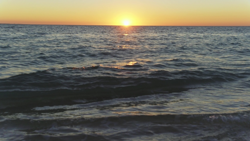 Sun setting down over calm ocean, only small waves on surface, Anakao, Madagascar
