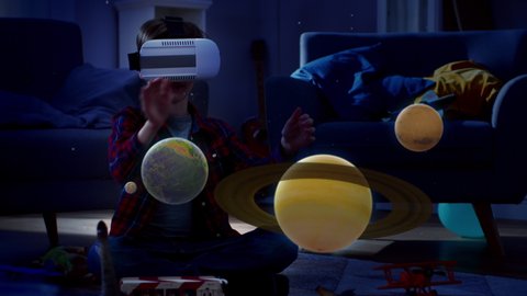 At Night Before Going to Bed: Little Boy Wearing Augmented Reality Headset Plays with Space Learning Software, With Gestures He Manipulates 3D Planets, Discovers Facts About Solar System and Cosmos