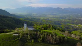 Jamnik, Slovenia - Panoramic view of sun over the church of St. Primoz in Slovenia near Jamnik with beautiful clouds and Julian Alps at background