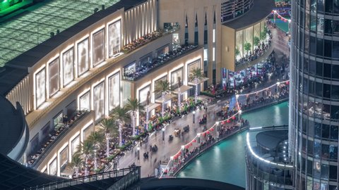 Lots of tourists walking near foutains and shopping mall in Dubai downtown night timelapse. Aerial view to one of the largest shopping malls in the world. Balcony with viewpoint