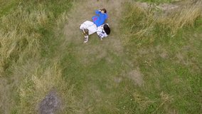 Aerial view of three girlfriends in long summer dresses laying on a high hill at the river. Connection with nature, rural life, friendship. Drone shooting, top view. Camera moving up